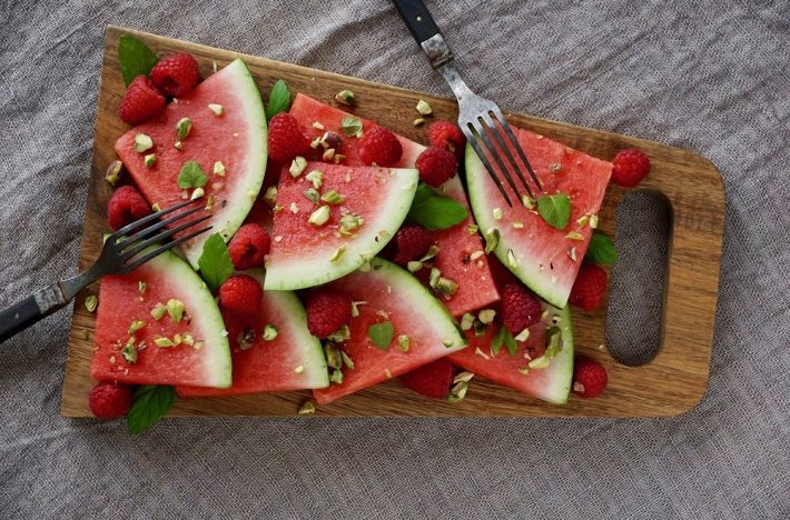 Vattenmelon på bricka med hallon, pistagenötter och mynta