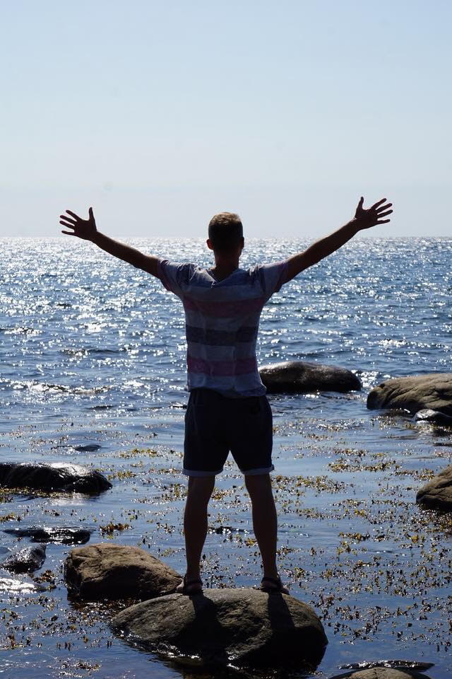 En person står på en sten i strandkanten, representerar frisk mage med probiotika trots IBS