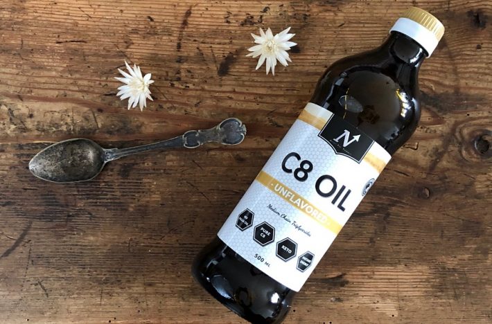 En flaska med MCT-olja av märket Nyttoteket C8 Oil tillsammans med en matsked olja