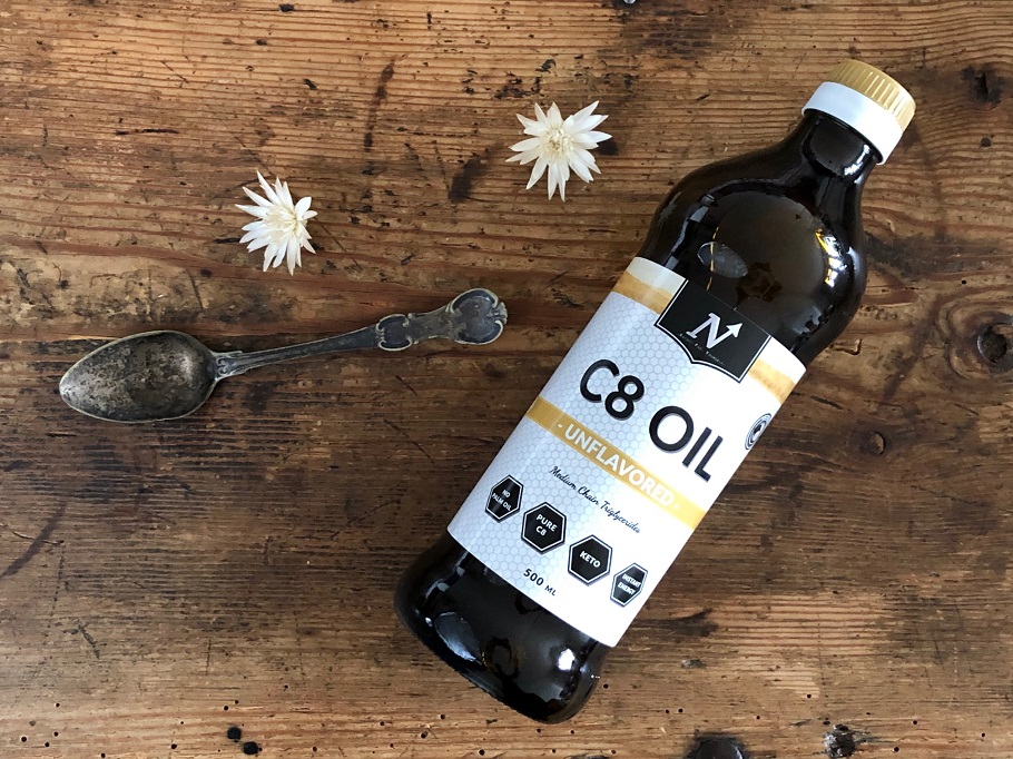 En flaska med MCT-olja av märket Nyttoteket C8 Oil tillsammans med en matsked olja