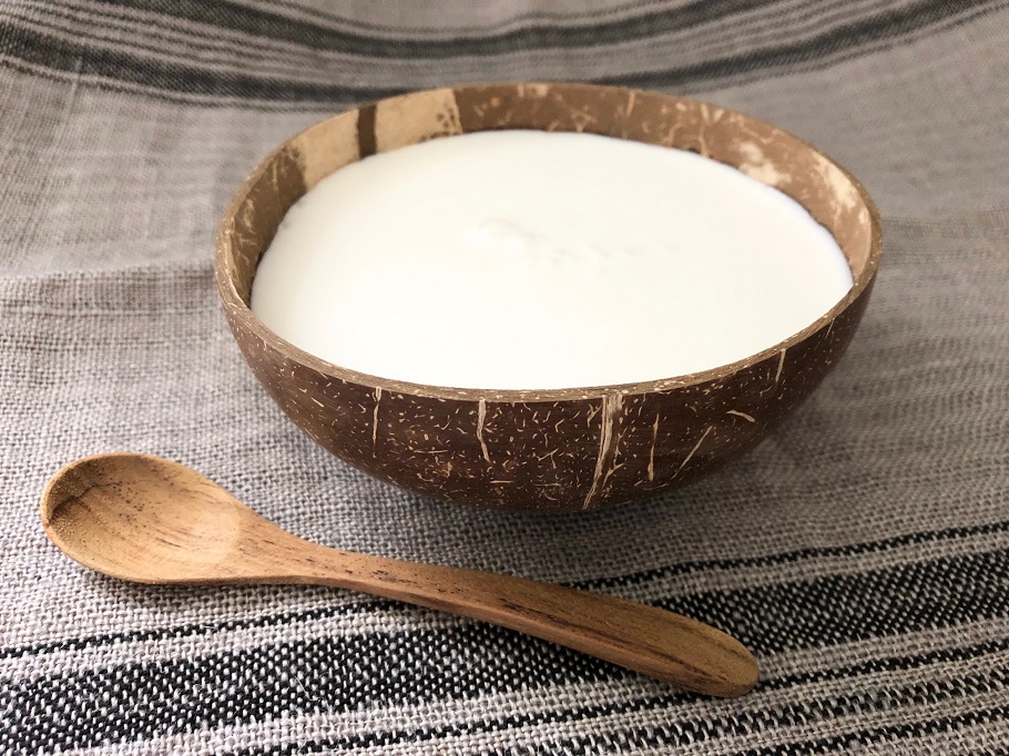 kokosyoghurt i en skål av en halv kokosnöt med en sked bredvid