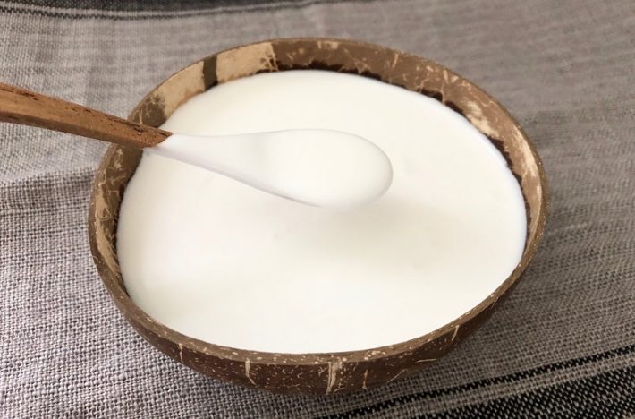 kokosyoghurt i en skål av kokosnöt och en sked fylld med yoghurt