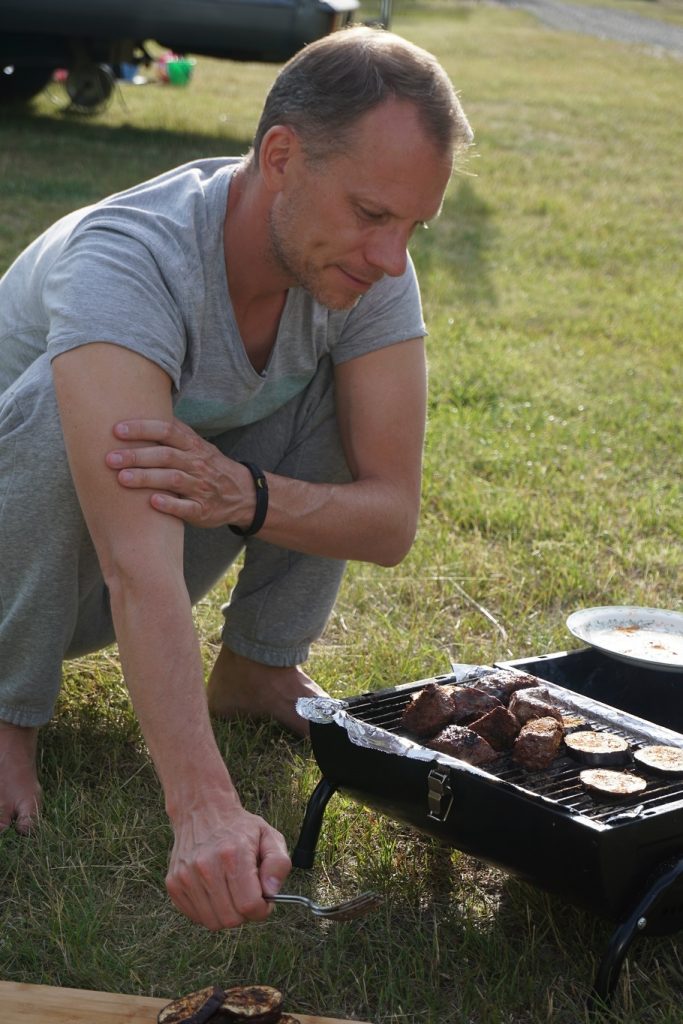 Sitta på huk och laga mat på en campingplats